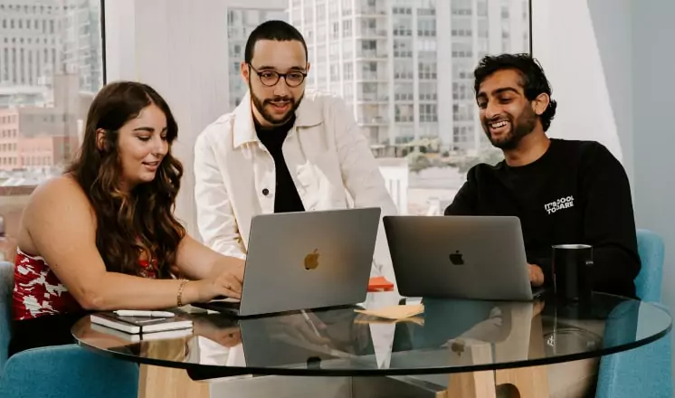 A group of people sitting around a table at a digital marketing agency, working on their laptops.